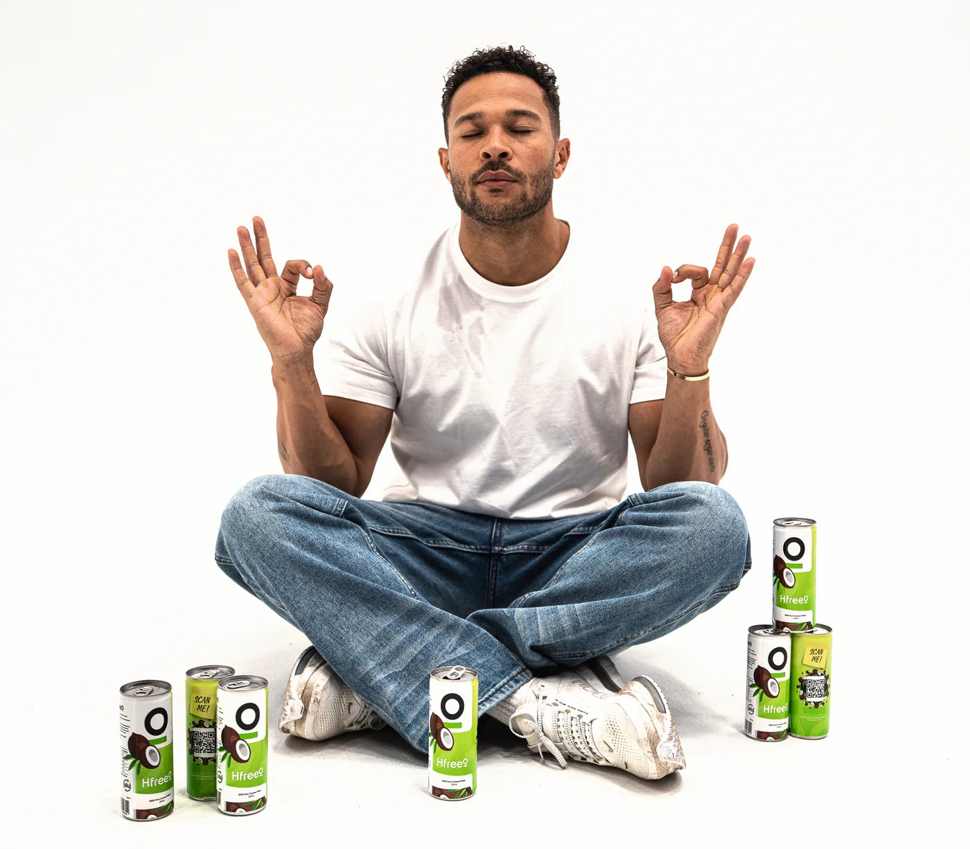 Cole Anderson-James sat cross-legged on the studio floor, eyes closed, hands in a meditation pose, with HfreeO cans round him.